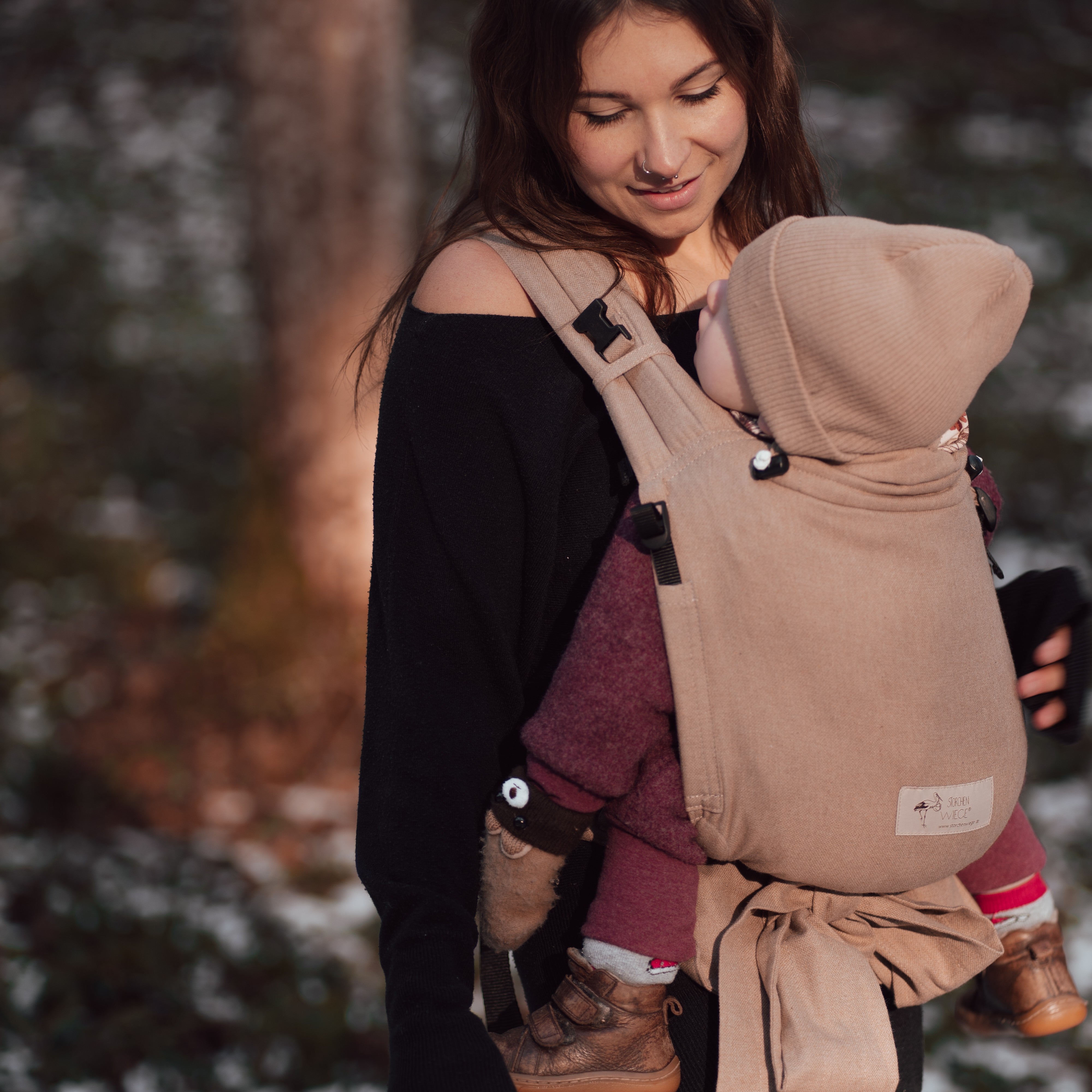 Babycarrier Sand in use, featuring comfortable padded straps and secure buckle, suitable for newborns to 15 kg.