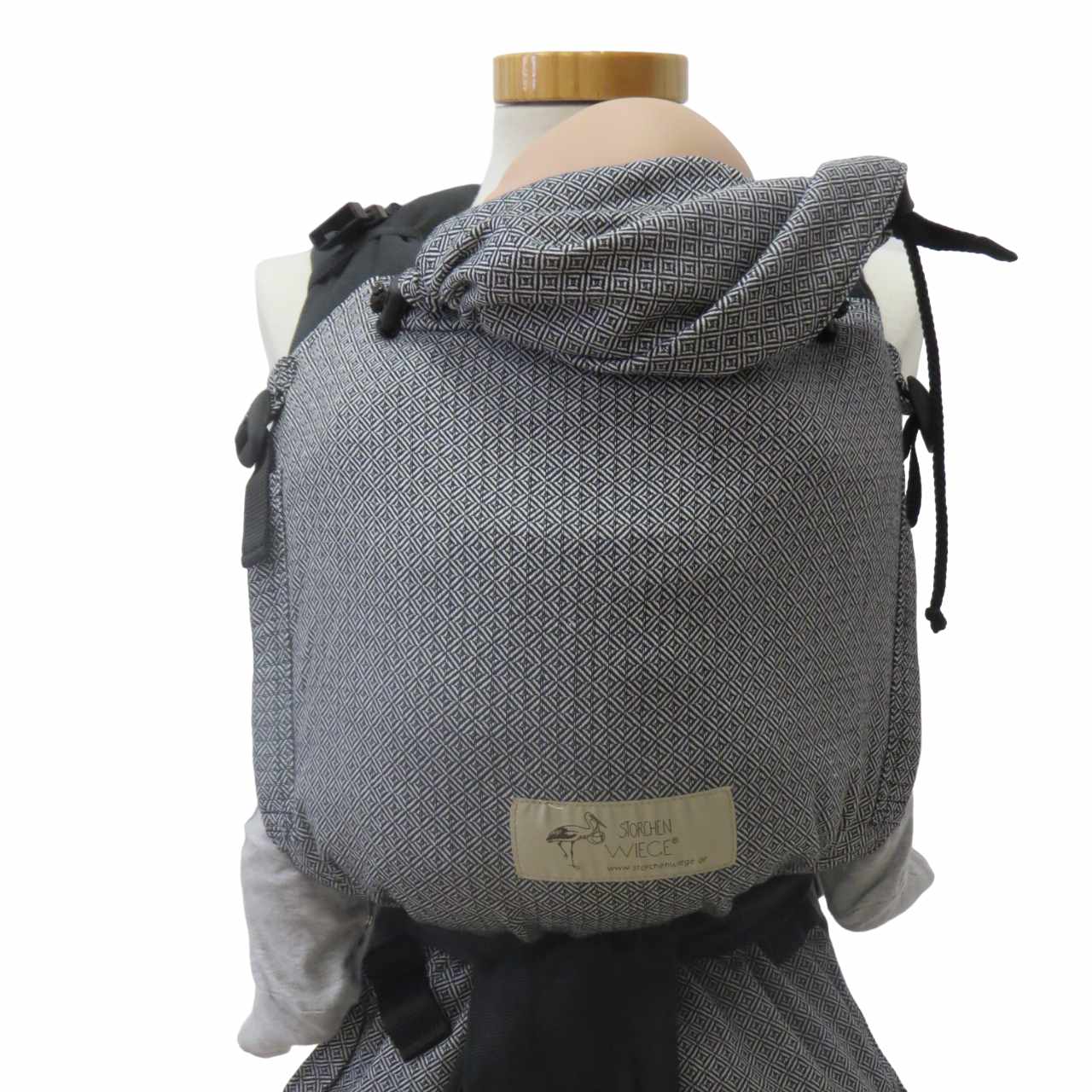 Black and white Babycarrier Leo with adjustable half-buckle, soft webbed design, padded straps, and infant head support.