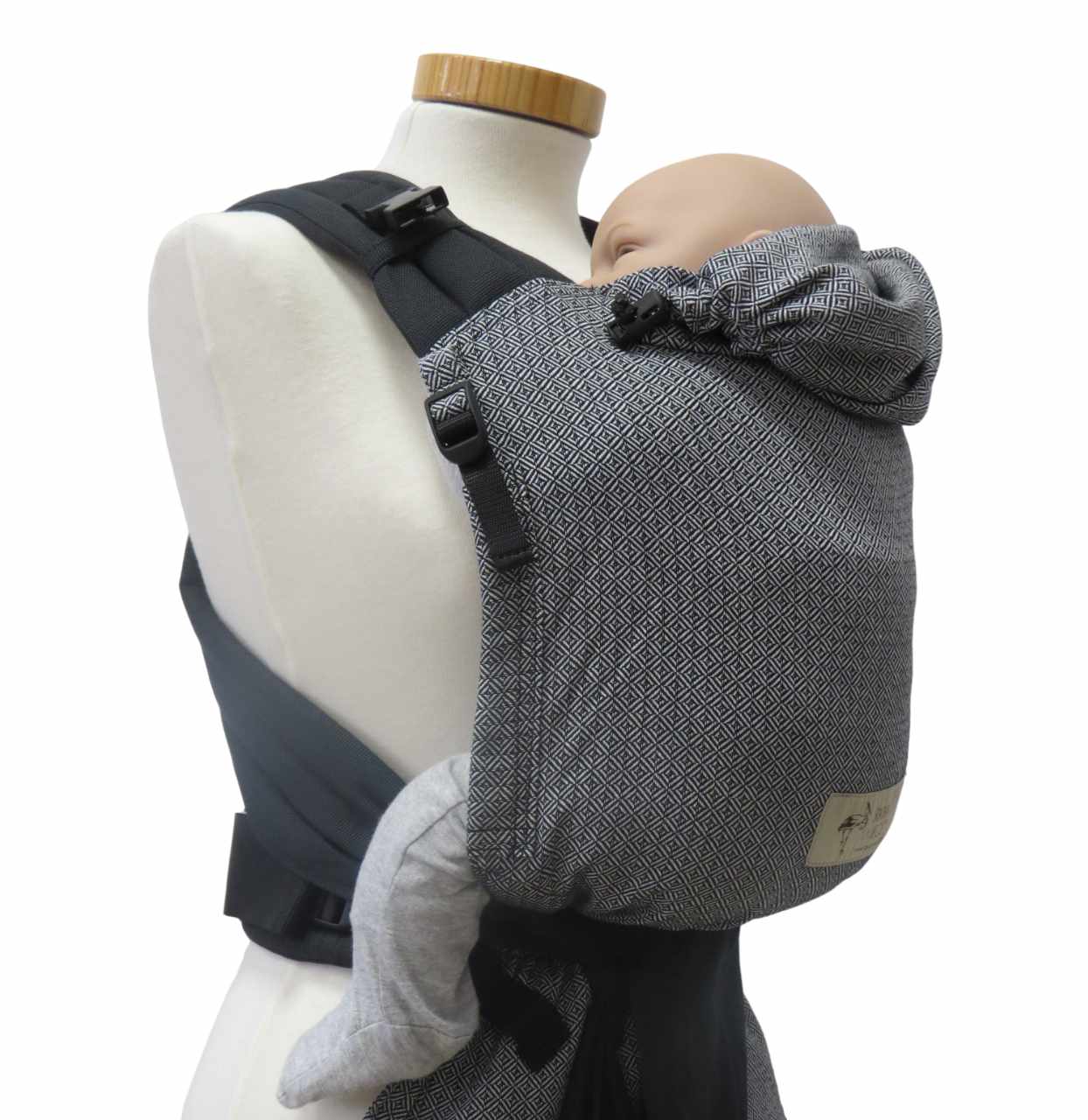 Babycarrier Leo Schwarz Weiss with black straps and patterned fabric, suitable for newborns to 15 kg.