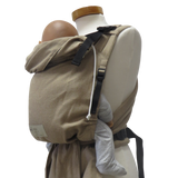 Babycarrier in sand color with adjustable straps and padded waistband, suitable from 3.5 kg to 15 kg, made from 100% cotton.