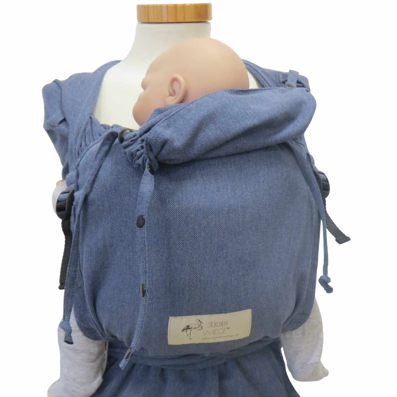 Denim-style wrap baby carrier with broad shoulder straps and hip belt.
