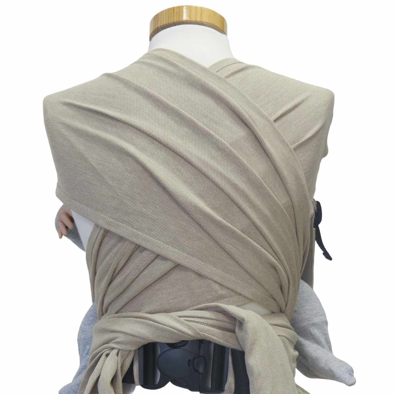 Natural-colored wrap baby carrier with wide shoulder straps and padded hip belt for newborns to 15 kg.