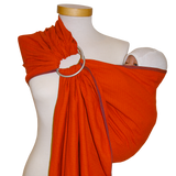 Ringsling Leo Orange with web pattern holding a baby, ideal for short distances and suitable for various carriers.