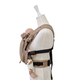 Valeno Sand baby carrier in beige with full buckle and padded straps carrying a doll in ergonomic front position