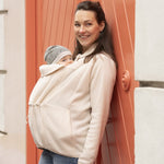 Woman wearing beige Mamalila Fleece Tragejacke babywearing jacket with baby in front pouch outdoors