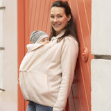 Woman wearing beige Mamalila Fleece Tragejacke babywearing jacket with baby in front pouch outdoors