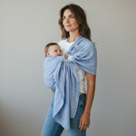 Frau trägt Baby in hellblauem Leinen-RingSling KRISTALLKLAR Babytrage für 3,5-15 kg mit sicherem Halt und atmungsaktivem Material