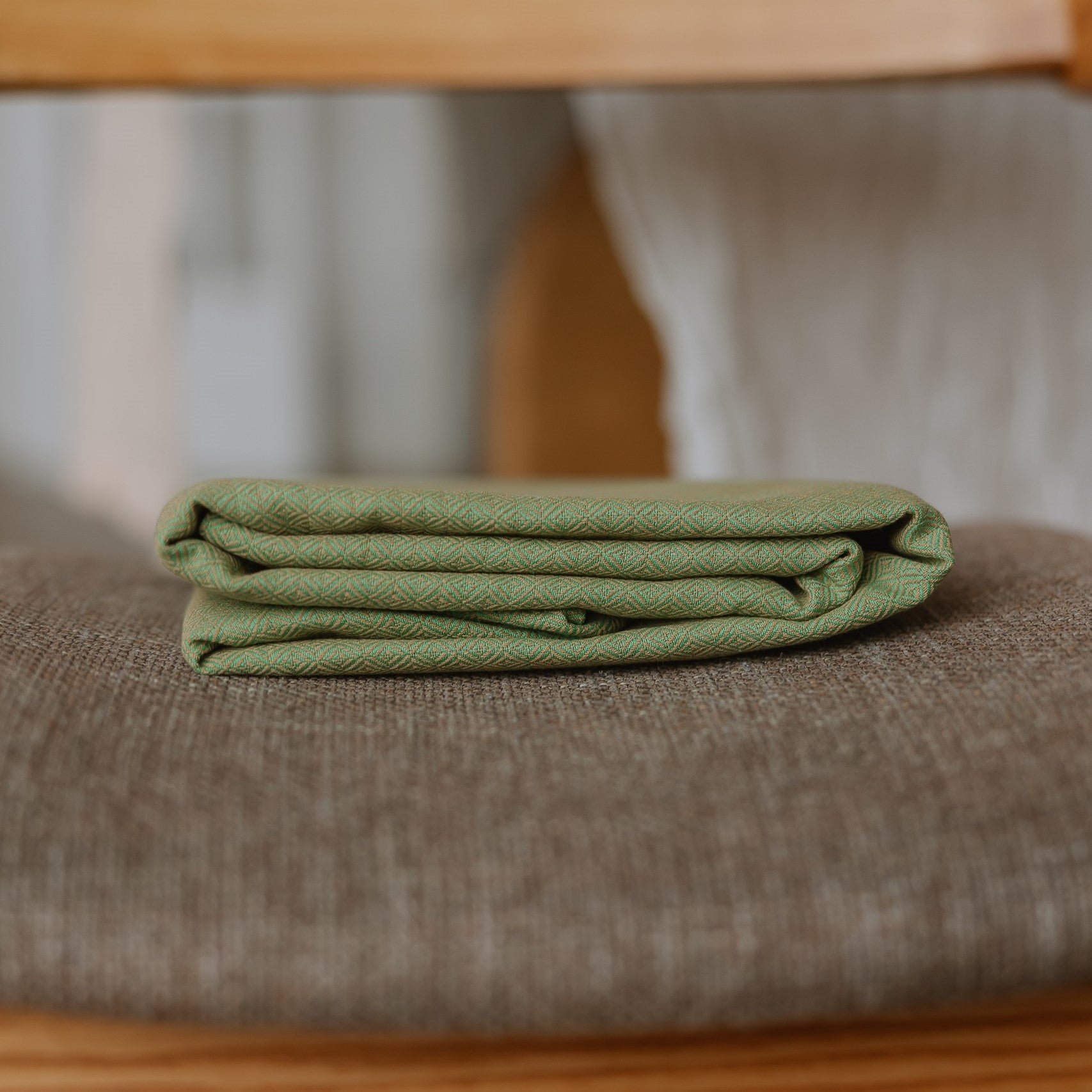 Ringsling Leo Grün mit zartem Webmuster aus Baumwolle auf Stoff.