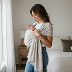 Frau trägt Baby im Ringsling Mondstein Tragetuch aus 100% Baumwolle mit zartem Webmuster in hellem Beige