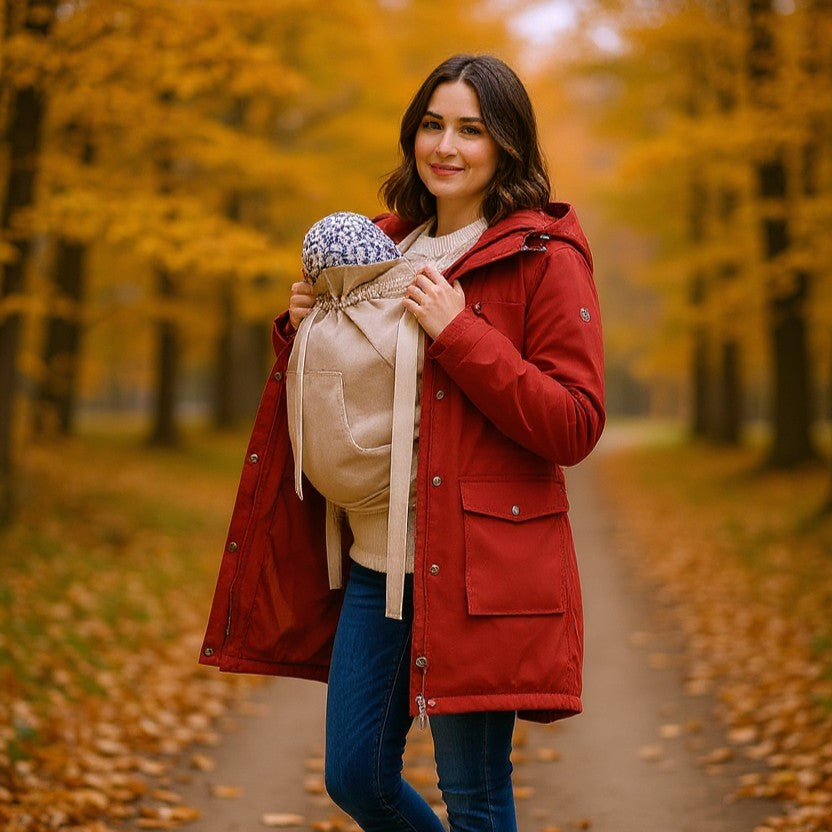 Frau trägt Baby im Storchenwiege Tragecover bei herbstlichem Waldspaziergang
