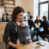 Mutter trägt Baby in Valeno Graphit Babytrage mit gepolsterten Trägern und Brustgurt in Café