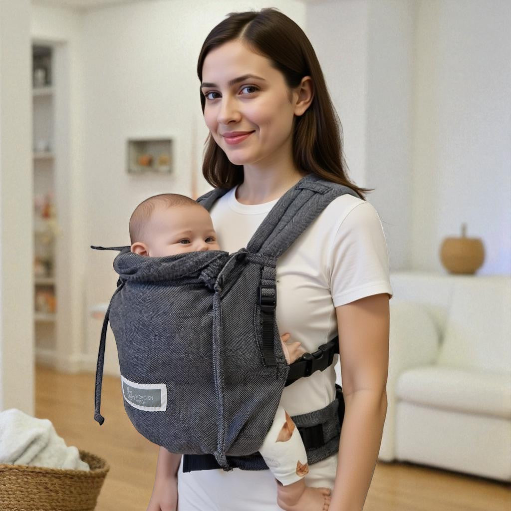 Valeno Graphit baby carrier with adjustable straps and chest belt, worn by a woman carrying a baby indoors