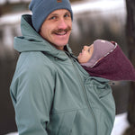 Man wearing Mamalila Softshell Tragejacke babywearing jacket with infant in hood pouch outdoors in winter